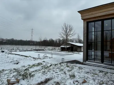 a building with snow on the ground next to a field at Hidden Secret of Nature in Neeroeteren