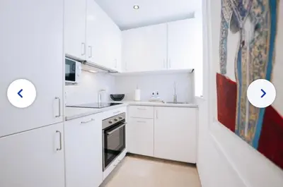 a kitchen with white cabinets and a painting on the wall at Chic et cosy idéal pour un séjour à Liège in Liège