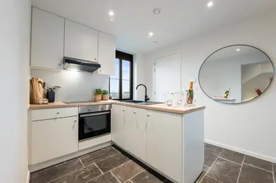a kitchen with white cabinets and a mirror at Huys van Haeghe in Zoutleeuw