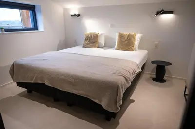 a bedroom with a large bed with white sheets and a window at Le Marzelheide 3 in Lontzen