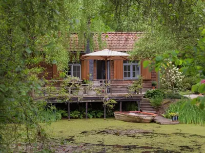 a wooden house with an umbrella and a boat at Fishing Chalet, Opglabbeek in Oudsbergen
