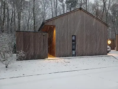 a barn with a door in the snow at Lysdann Zutendaal in Zutendaal