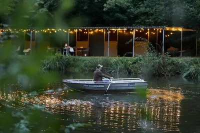 a man is rowing a boat on the water at Homestorys Nature Resort - Lakeview Pavilion in Eupen