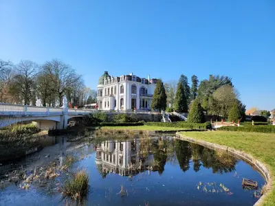 a white house with a bridge over a river at Kasteel Rosmeulen in Mall