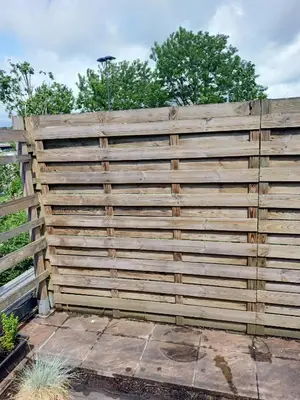 a wooden fence in a yard with trees in the background at La Vie en Rose in Ensival