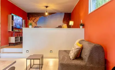 a living room with orange walls and a couch and a table at Charming 2-Bedroom House Rental in Dalhem, Belgium in Dalhem