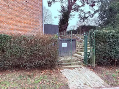 a gate in front of a brick building with stairs at Hoeve Verdre - De Knechtenwoning in Heers