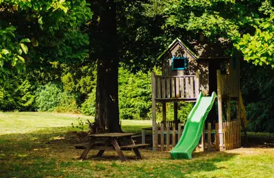 a playground with a slide and a tree at Hoeve Verdre - De Knechtenwoning in Heers