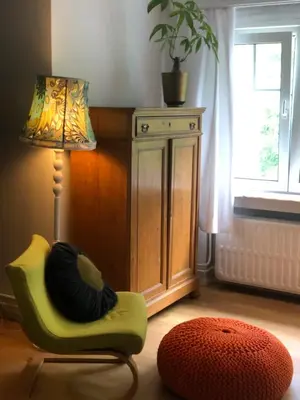 a living room with a green chair and a lamp at Villa des Bois Sauvages in Liège