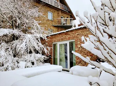 a house with snow covered trees in front of it at Au coeur de l'Ardenne - Peaceful loft in Baelen
