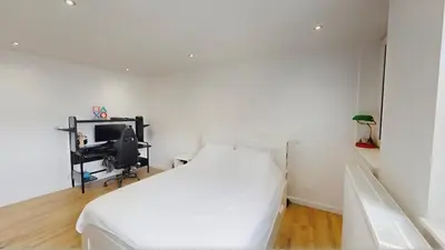 a white bedroom with a bed and a desk at Home cinema in Liège