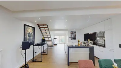 a kitchen and living room with white walls and a staircase at Home cinema in Liège