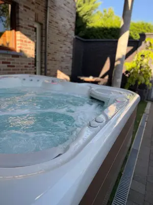 a large hot tub in a backyard with blue water at Wellness L'eau Belle in Beringen