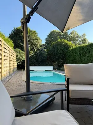a swimming pool with a table and an umbrella at Wellness L'eau Belle in Beringen