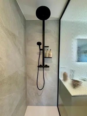 a shower with a black shower head in a bathroom at Au refuge des 3 pommes in Blégny