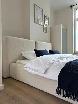 a bedroom with a bed with white sheets and blue pillows at Luik city center in Liège