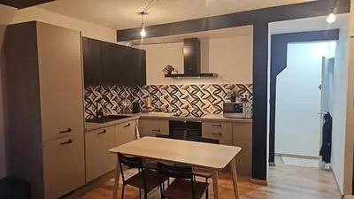 a kitchen with a table and some chairs in it at Logement Sam in Liège