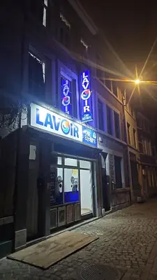 a lit up building with a sign on a street at Logement Sam in Liège