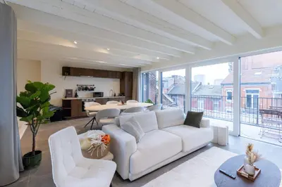 a living room with a white couch and a large window at Theodore Schwann - duplex centre de Liège in Liège