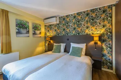 a bedroom with a large bed with two pillows at Hotel Brasserie de Klok in Zutendaal
