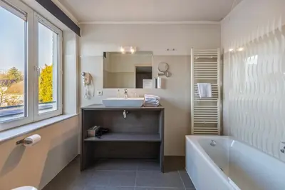 a bathroom with a sink and a tub and a mirror at Hotel Brasserie de Klok in Zutendaal