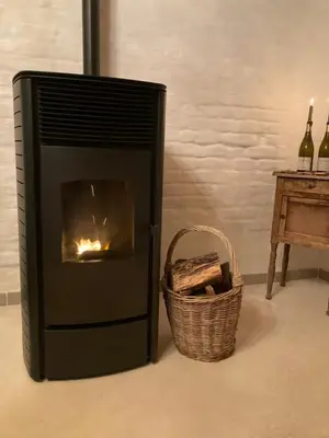 a fireplace with a basket next to a table with wine bottles at Maison Lion Luxe vakantiewoning in Borgloon