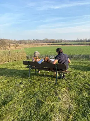 a man and a woman sitting on a bench with a dog at Maison Lion Luxe vakantiewoning in Borgloon