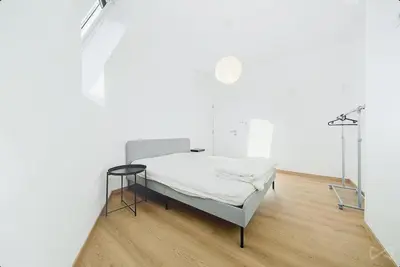 a white room with a bed and a wooden floor at Logement temporaire haut de gamme Particuliers & entreprises in Liège