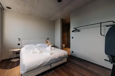 a bedroom with a bed with white sheets and pillows at Coliving - Bord de Meuse - L'écrin Vert in Oupeye