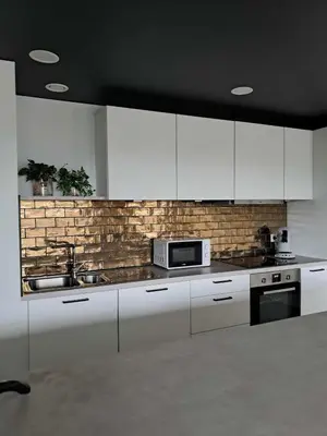 a kitchen with white cabinets and a brick wall at Chez Vincent, parking gratuit in Liège