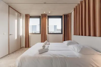 a bedroom with a large white bed with windows at Coliving - Bord de Meuse - L'atelier de la Meuse in Oupeye