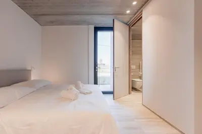 a bedroom with a large white bed with towels on it at Coliving - Bord de Meuse - L'instant in Oupeye