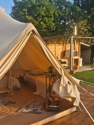 a tent with a bed and a table in a yard at Glamping met paarden in Nieuwerkerken