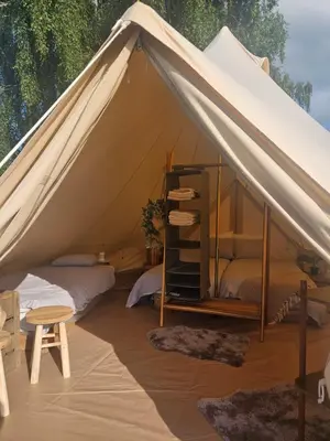 a canvas tent with two beds and a stool at Glamping met paarden in Nieuwerkerken