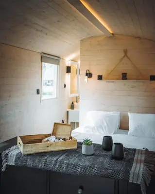 a bedroom with a bed and a wooden wall at Camping Papillon Kinrooi - Pipowagen met terras in Kinrooi