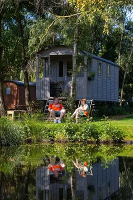 two people sitting in chairs in front of a tiny house at Camping Papillon Kinrooi - Pipowagen met terras in Kinrooi