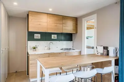 a kitchen with a wooden counter top and white chairs at Camping Papillon Kinrooi - Vakantiehuis Familie 6P in Kinrooi