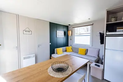 a kitchen and living room with a table and yellow pillows at Camping Papillon Kinrooi - Vakantiehuis Familie 6P in Kinrooi