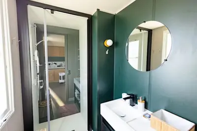 a bathroom with a green wall and a mirror at Camping Papillon Kinrooi - Vakantiehuis Familie 6P in Kinrooi