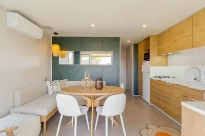 a kitchen and dining room with a wooden table and white chairs at Camping Papillon Kinrooi - Vakantiehuis Premium 4P in Kinrooi