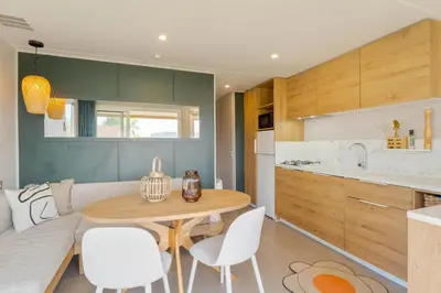 a kitchen with a wooden table and white chairs at Camping Papillon Kinrooi - Vakantiehuis Premium 4P in Kinrooi