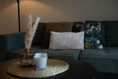 a living room with a couch and a table with a candle at Camping Natuurlijk Limburg - Studio 1 in Voeren