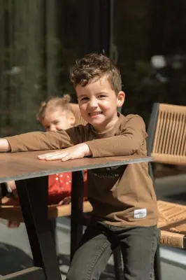 a young boy is standing at a table at Camping Natuurlijk Limburg - Studio 1 in Voeren