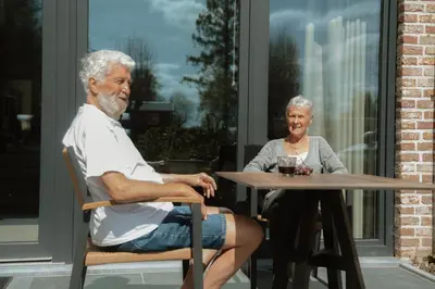 an older man and a woman sitting at a table at Camping Natuurlijk Limburg - Studio 1 in Voeren