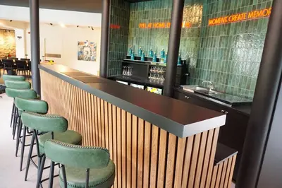 a bar with a row of green stools at L'Orée des Thermes in Chaudfontaine