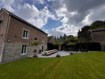 a yard with a bench and a brick building at L'Orée des Thermes in Chaudfontaine