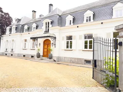 a large white house with a wooden door at Héritage Collection - Suites in Verviers