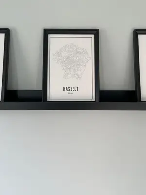 a shelf with three framed pictures on a wall at JoHa Haus in Hasselt