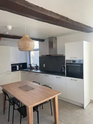 a kitchen with a wooden table and a kitchen with white cabinets at Le Havre de paix in Oupeye