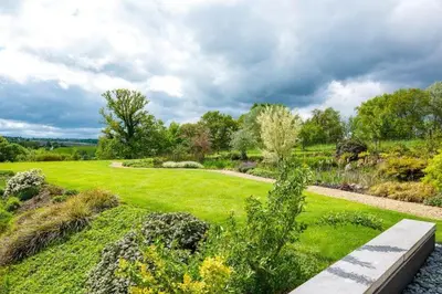 a garden with a green lawn with trees and bushes at Villa Bianca in Dalhem